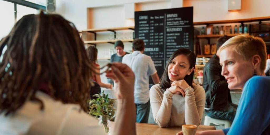 Diverse group networking at a coffee meetup, illustrating supportive connections during career transitions.